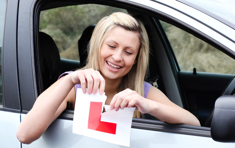 Girl tearing L plates after passing driving test