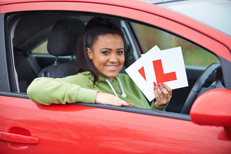 Young girl holding L plates in a red car